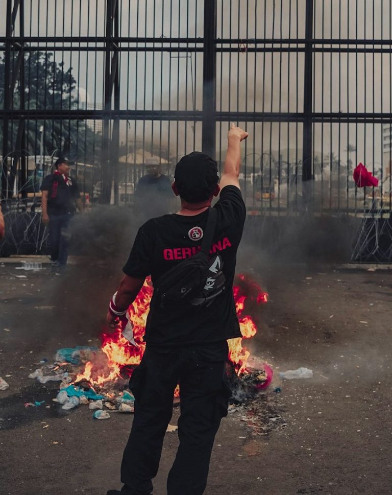 Global Security Education Two armed officers in tactical gear apprehend a restrained man in an indoor setting.